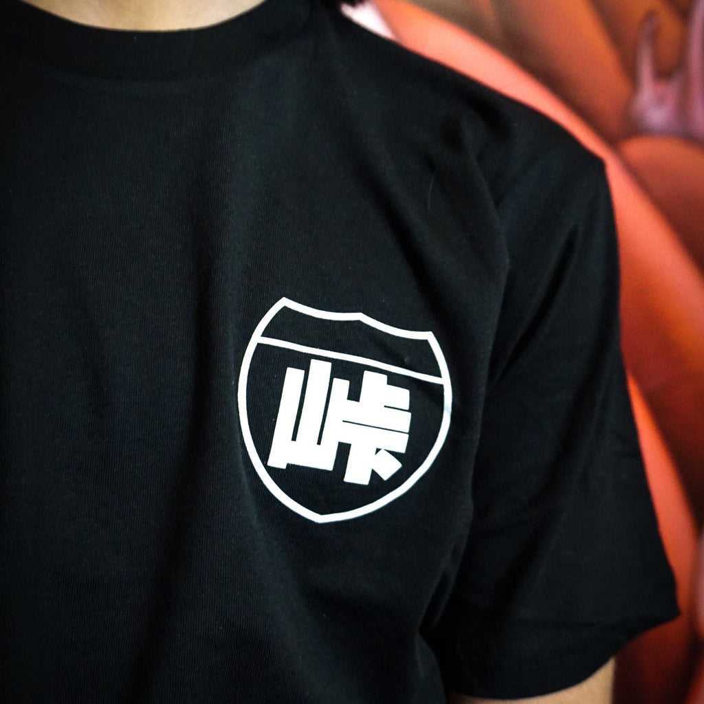 Black cotton unisex short-sleeved T-shirt with Japanese tōge roadway chest emblem on front in white ink.