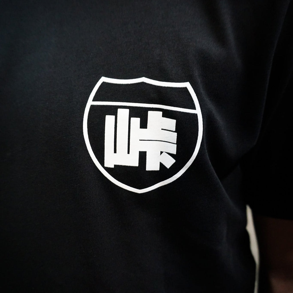 Black cotton unisex short-sleeved T-shirt with Japanese tōge roadway chest emblem on front in white ink.