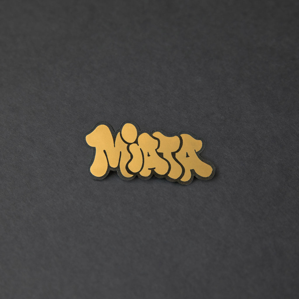 Black and gold laser-engraved acrylic Miata hair clip.
