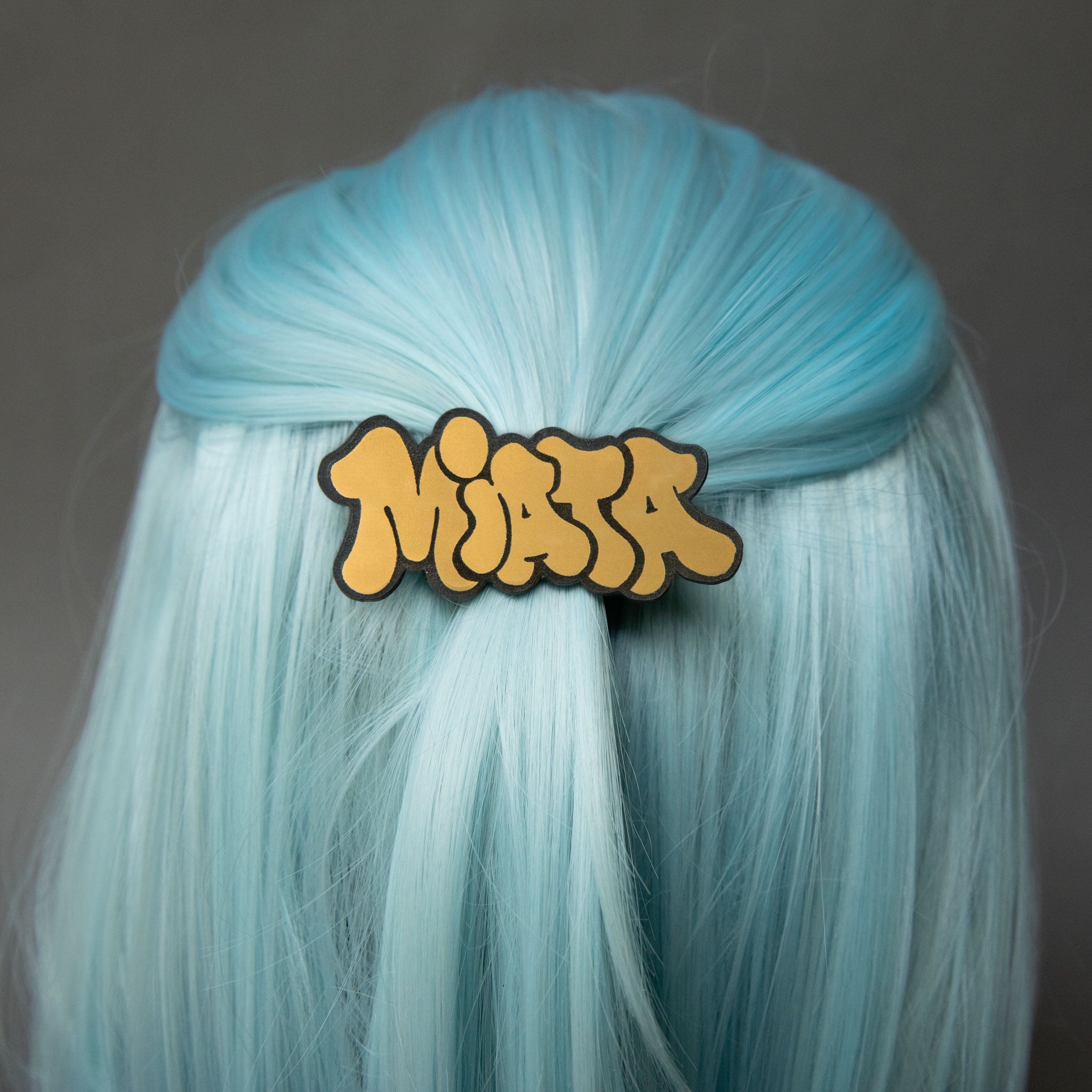 Black and gold laser-engraved acrylic Miata hair clip.