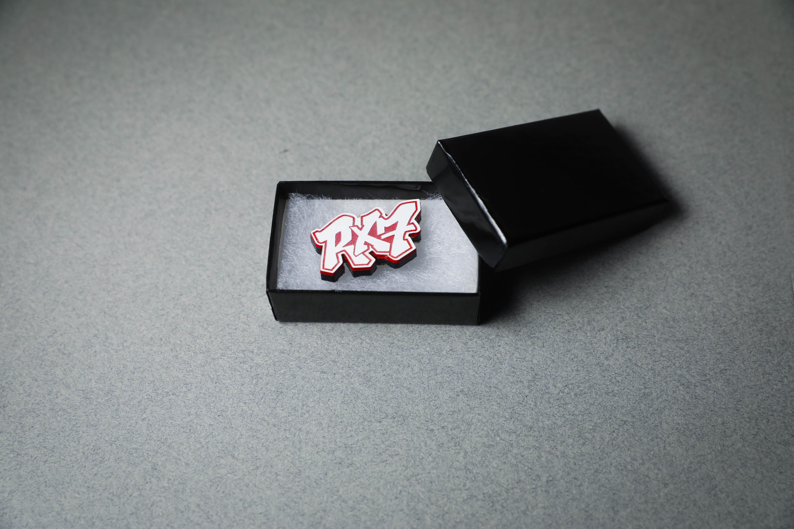 red RX7 acrylic lapel pin in jewelry box